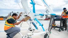 Dos operarios cargan un paquete de Amazon en un dron MK30 de Prime Air sobre una plataforma de lanzamiento