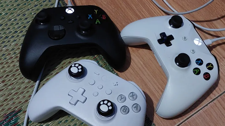 Dos mandos de Xbox de primera parte con cables USB y un tercer mando de otra marca