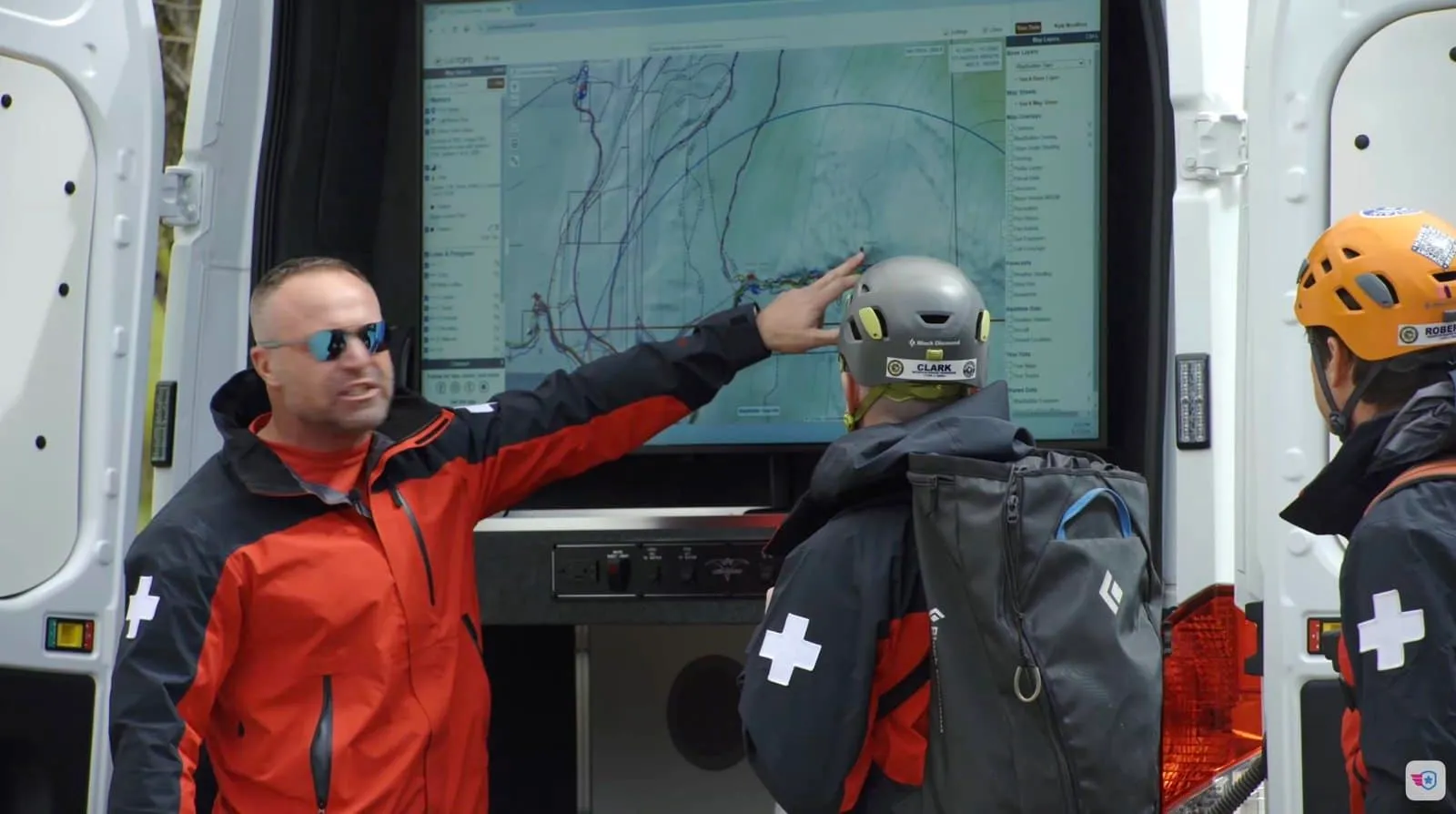 Nordfors explica un área de búsqueda sobre un mapa topográfico en la pantalla de la furgoneta de rescate