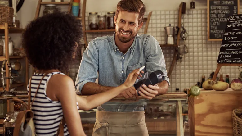 Una persona realiza un pago sin contacto con el móvil en un comercio