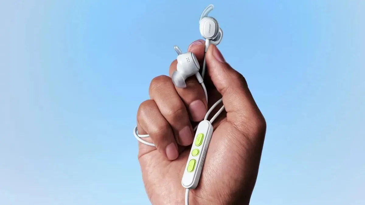 A hand holding the earbuds and the in-line remote, with green buttons