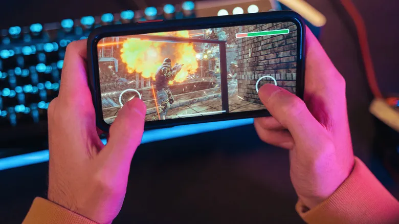 Persona jugando a un shooter de acción en un teléfono móvil