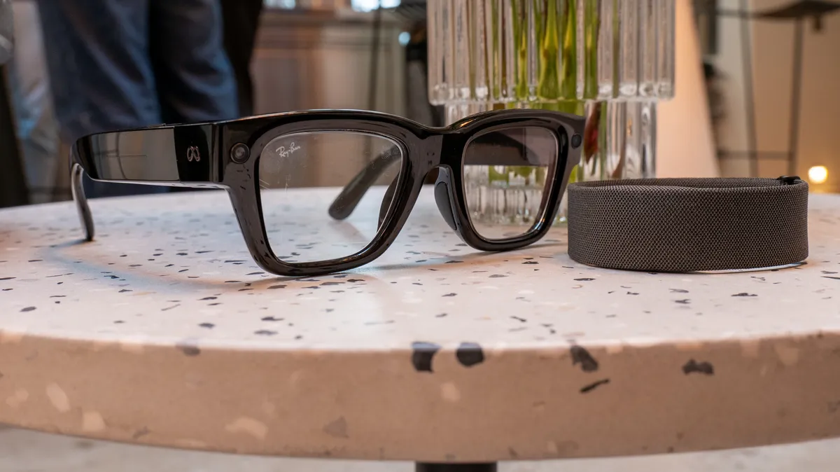 Gafas inteligentes Meta Ray-Ban Display de montura negra junto a su estuche sobre una superficie morada