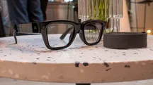 Gafas inteligentes Meta Ray-Ban Display de montura negra junto a su estuche sobre una superficie morada