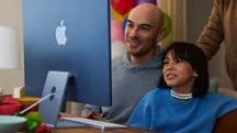 An adult and a child in front of an Apple computer reviewing the screen together