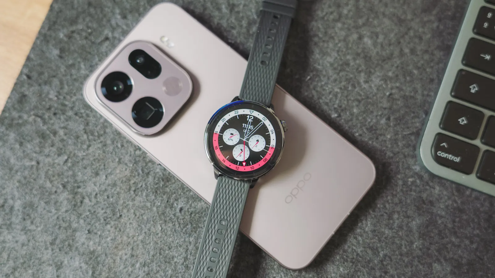 Reloj inteligente OPPO Watch X2 Mini con esfera analógica descansando sobre la parte trasera de un teléfono OPPO Find X9 en color rosa