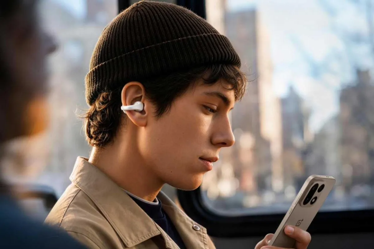 Person with a clip-on earbud on the ear while holding a phone