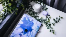 Closed Apple laptop beside a white speaker and plants on a table