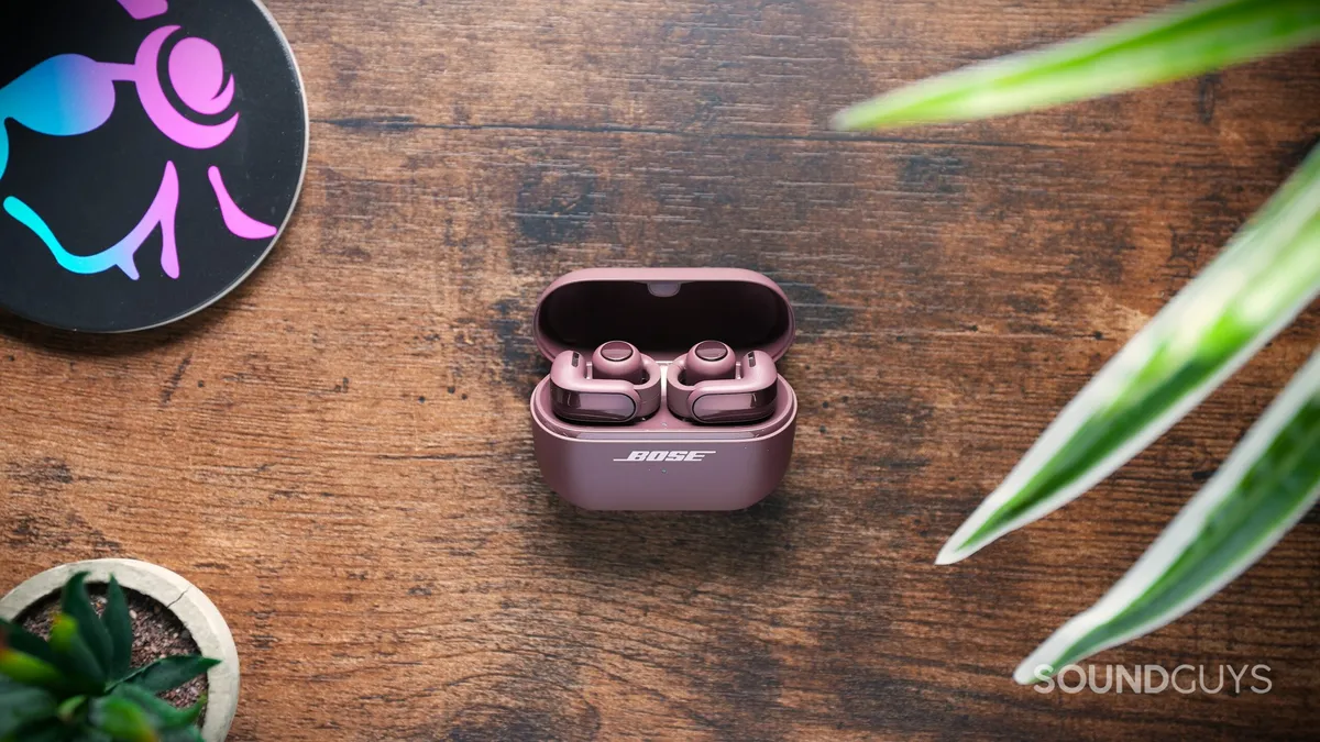 Auriculares Bose Ultra Open Earbuds de segunda generación en su estuche de carga abierto sobre una mesa de madera