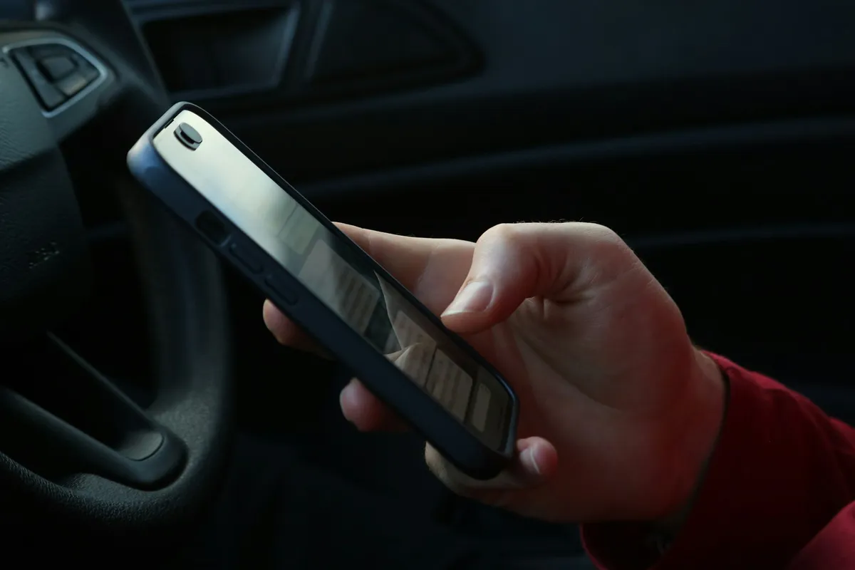 Persona consultando datos en un smartphone en el interior de un coche