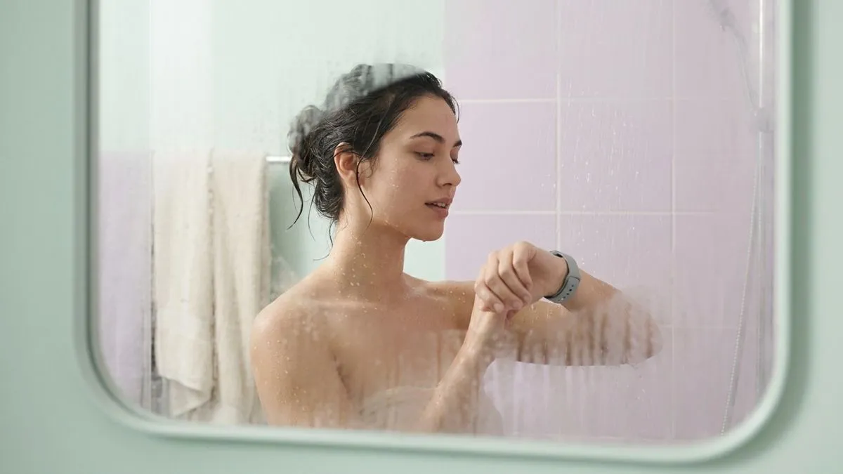 Persona con un reloj inteligente en la muñeca dentro de un cuarto de baño con vapor