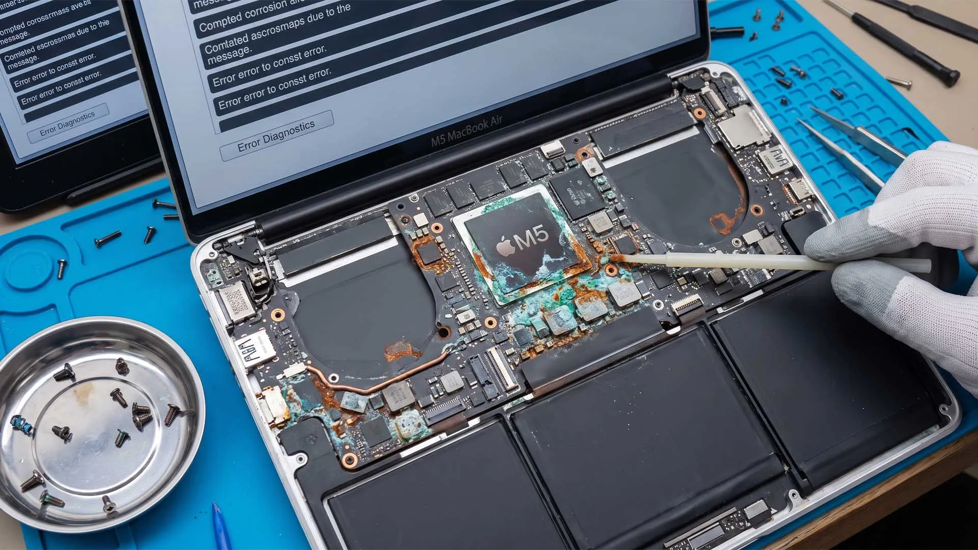 MacBook Air M5 abierto sobre una mesa de reparación, con la placa base a la vista y signos de corrosión