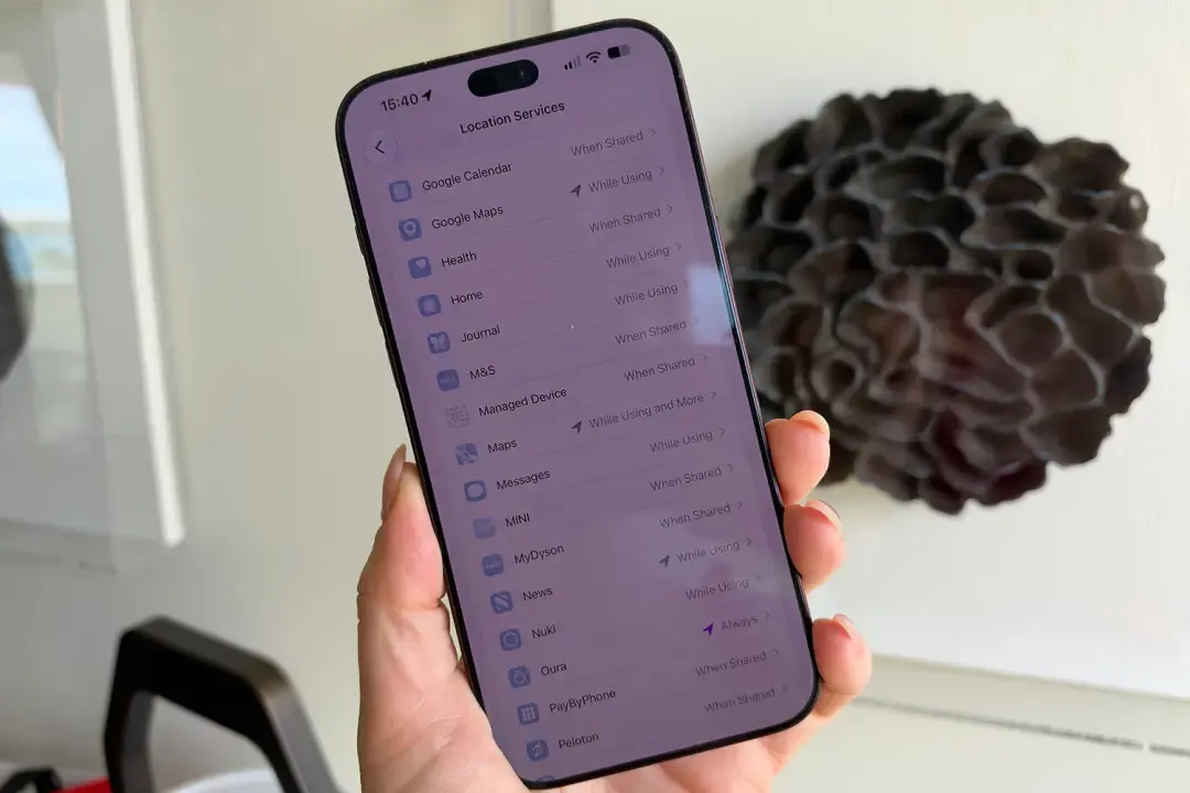 Mano sosteniendo un iPhone con la pantalla de Localización abierta y la lista de aplicaciones