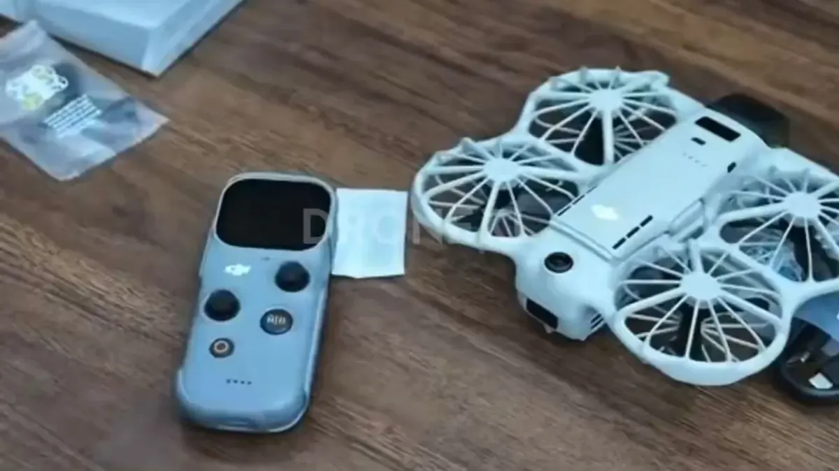 Dron DJI Neo 3 blanco con hélices protegidas por jaulas junto al mando DJI RC Mini con pantalla sobre una mesa de madera