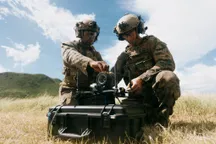 Two Marines load a simulated warhead onto a Neros Archer FPV drone fitted with a fiber-optic spool