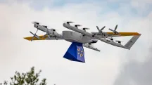 Wing delivery drone in flight carrying a Walmart box suspended on a tether