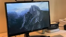 A Mac showing an Aerials screen saver with rugged mountains