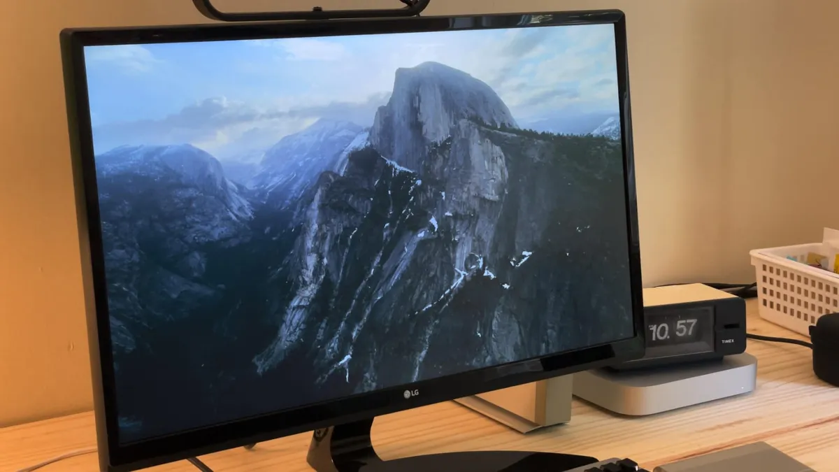 A Mac showing an Aerials screen saver with rugged mountains