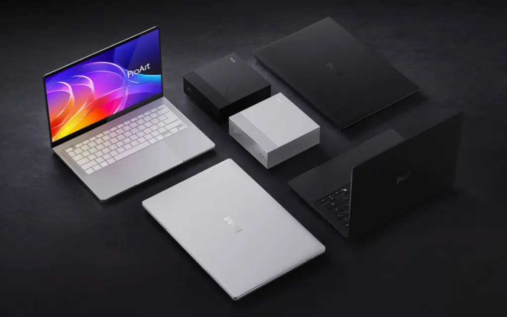 Varios portátiles Asus ProArt abiertos y cerrados junto a sus accesorios sobre una superficie oscura