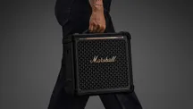 Una persona transporta el altavoz Marshall Bromley 150 sujeto por su asa retráctil
