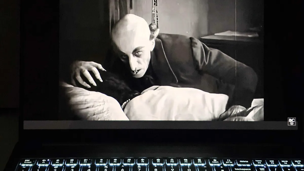 Portátil con teclado iluminado que muestra una escena de Nosferatu en su pantalla