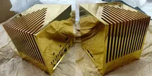 Chasis de oro del mini PC Kubb Fanless visto desde dos ángulos, con las ranuras de refrigeración en las caras laterales