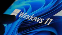 Dedo tocando el logotipo de Windows 11 en una pantalla a oscuras