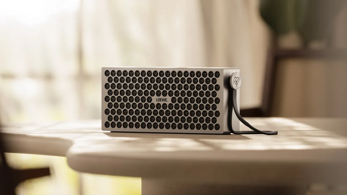 Altavoz Loewe Neo con acabado claro situado en un salón junto a otros objetos