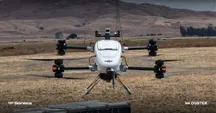 White Seneca drone hovering over a dry field, with the Seneca and Ouster logos and power lines in the background