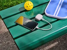 The POCO X8 alongside another device being charged via cable, demonstrating its reverse charging capability