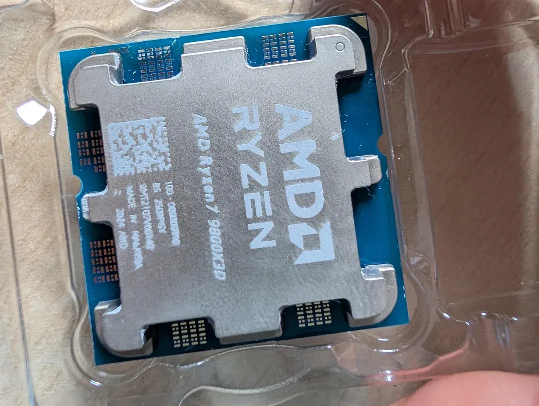 Procesador etiquetado como AMD Ryzen 7 9800X3D sobre su bandeja de plástico, con la PCB de tono azulado