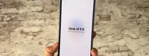 Un teléfono en mano muestra el aviso "One UI 9.0, el software está actualizado" frente a un muro de ladrillo