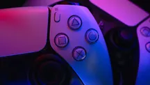 Mando DualSense de PlayStation 5 iluminado con luz azul y violeta sobre fondo oscuro