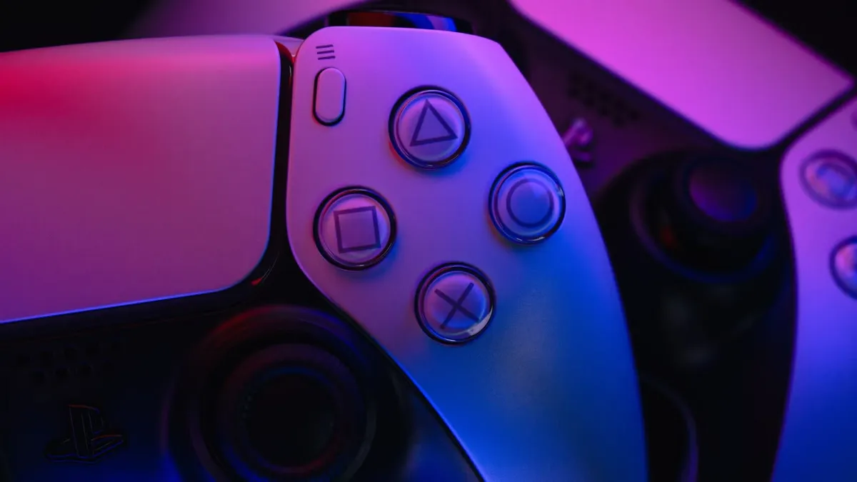 Mando DualSense de PlayStation 5 iluminado con luz azul y violeta sobre fondo oscuro