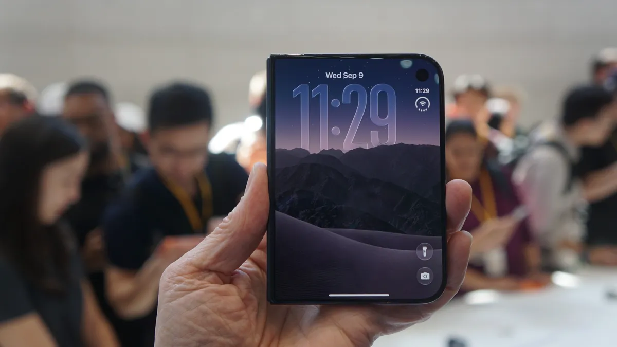 Apple's iPhone Duo folded and held in one hand, with the outer screen lit during a demonstration