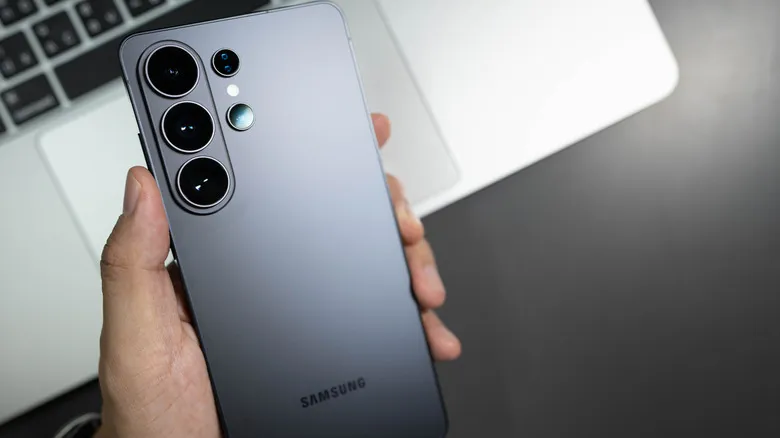 Persona sosteniendo un Samsung Galaxy S26 Ultra sobre el teclado de un portátil