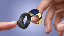 Two Pebble Index 01 rings held between fingers, one black and one gold with a blue button