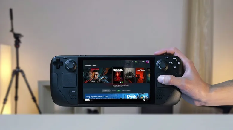 Manos sosteniendo una Steam Deck negra con la pantalla encendida