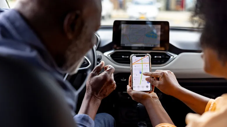 Dos personas usando un iPhone en el interior de un coche