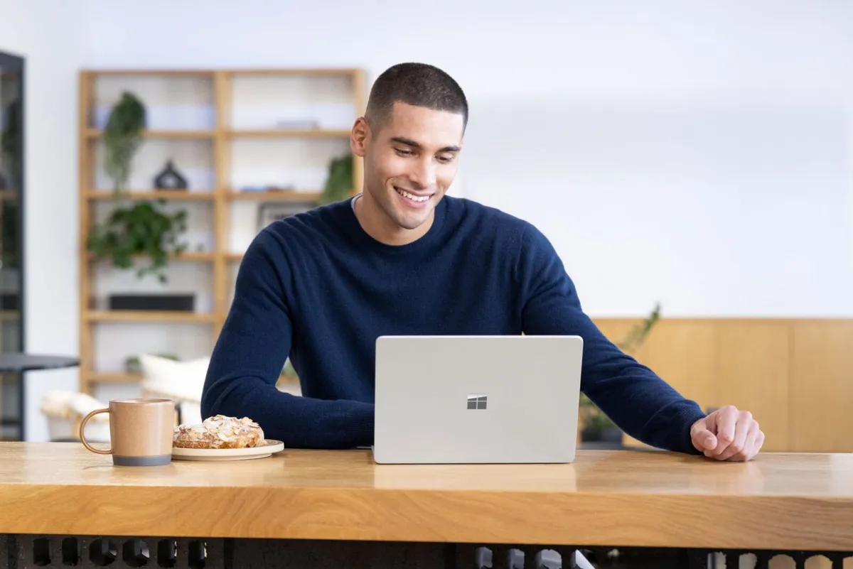A Surface laptop on a table next to a cup of coffee