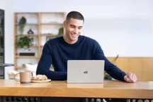 A Surface laptop on a table next to a cup of coffee