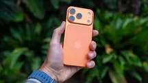 Mano que sostiene un iPhone naranja para usar la cámara