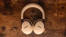 Auriculares Bose QuietComfort Ultra (2.ª generación) en color claro con detalles dorados, apoyados sobre una mesa de madera