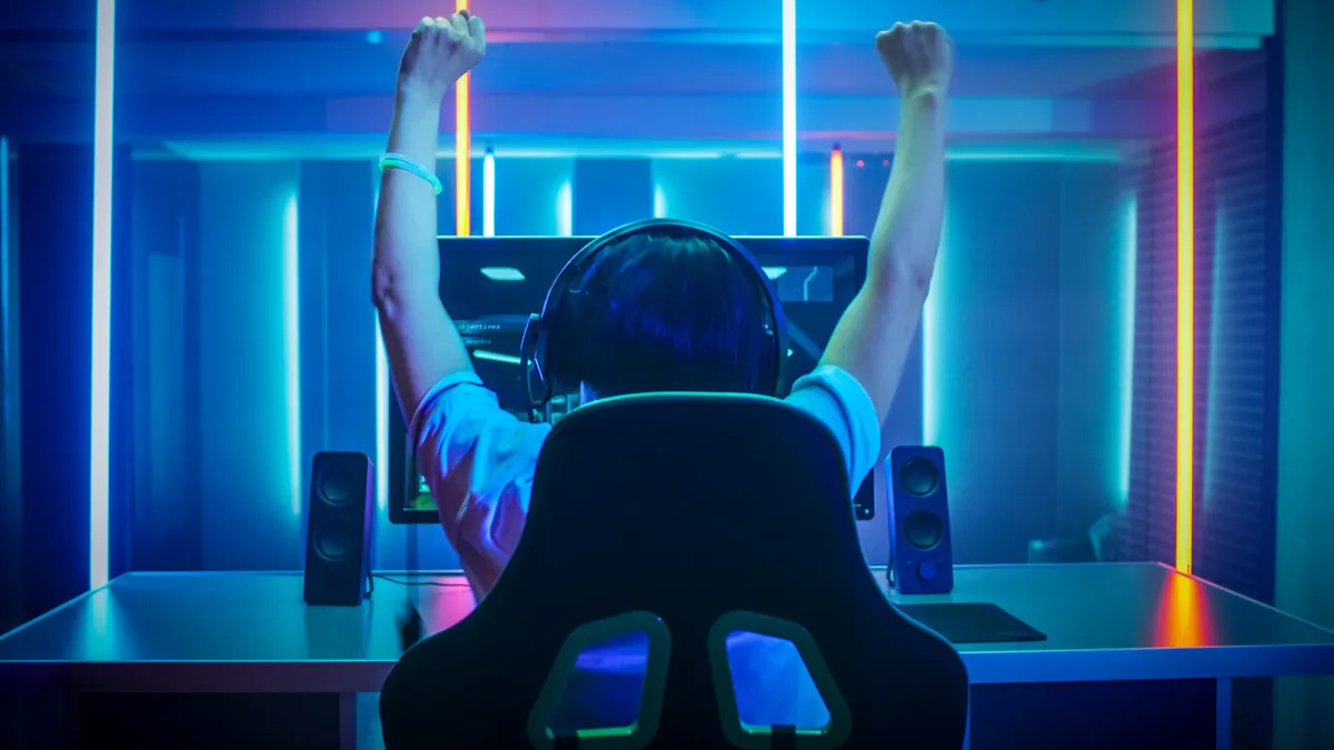 Jugador de PC sonriendo frente a un equipo de sobremesa con iluminación RGB