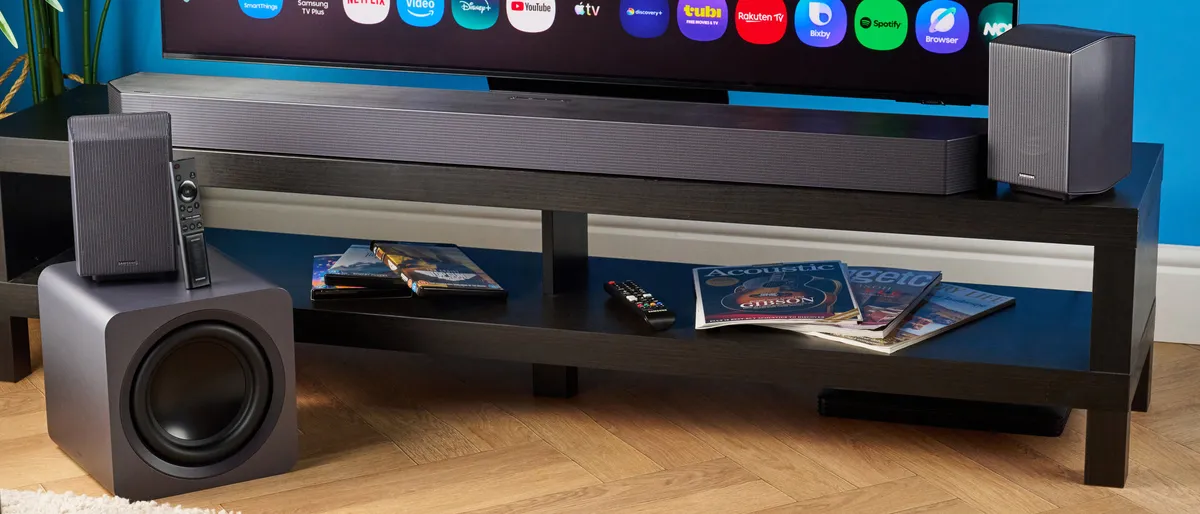 Barra Samsung Q990H bajo un televisor, con subwoofer y dos altavoces traseros