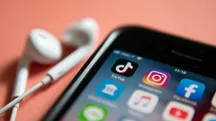 Auriculares con cable junto a un iPhone mostrando la pantalla de inicio