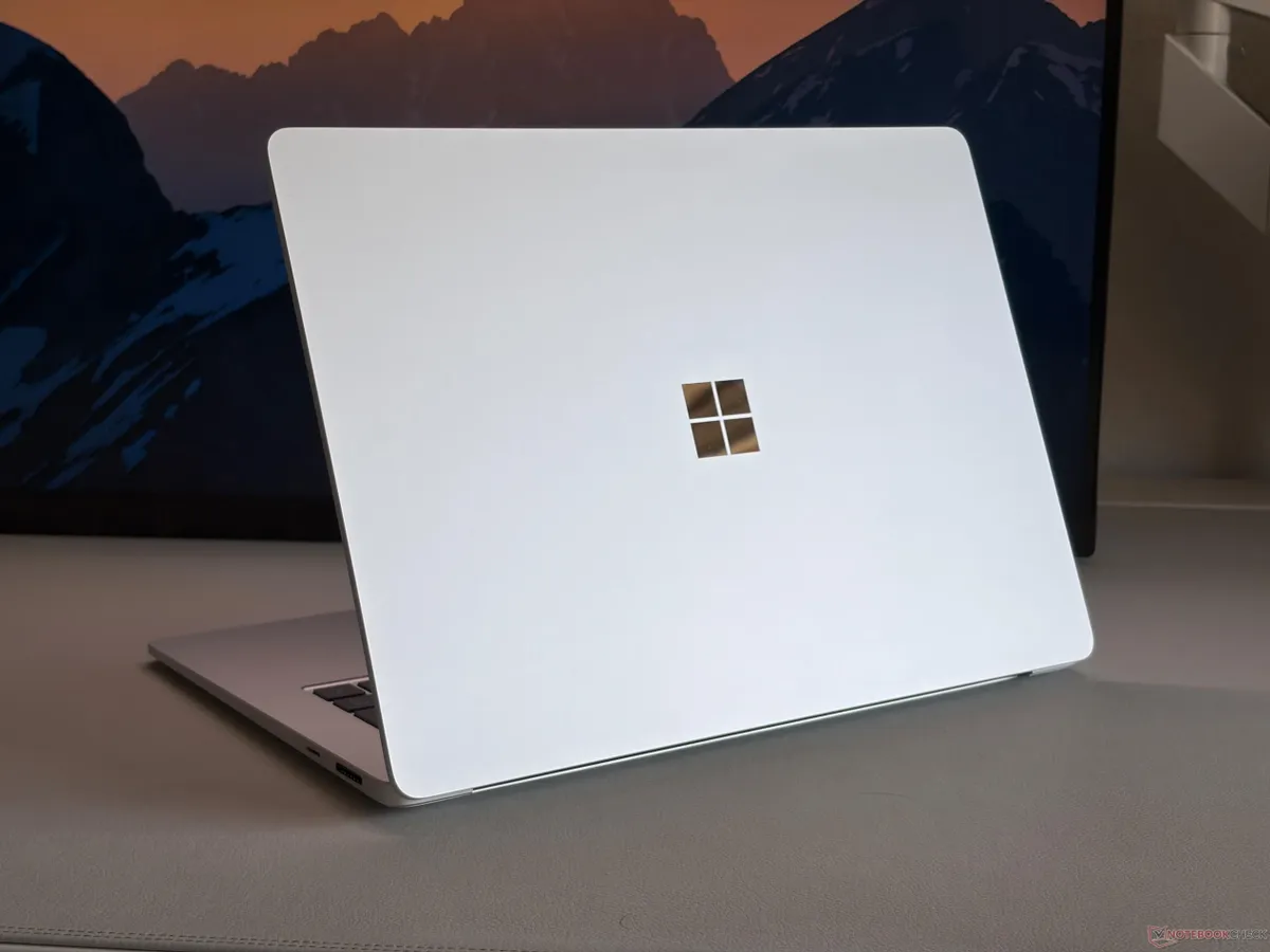 Surface Laptop plateado cerrado, visto de perfil, sobre una superficie gris con el logotipo de Microsoft en la tapa