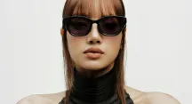 Portrait of a person wearing thick-framed black sunglasses against a white background