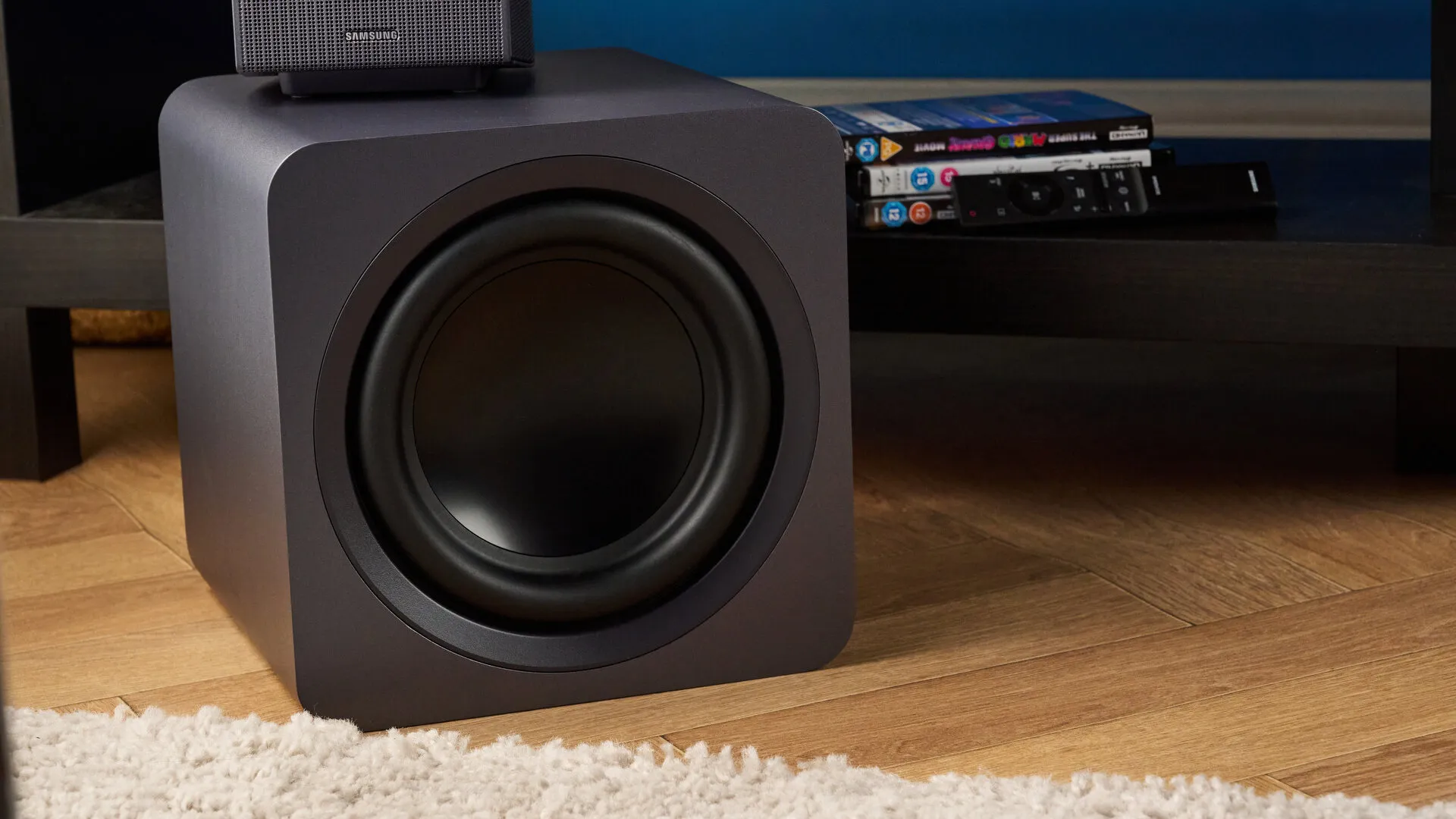Subwoofer de la Q990H colocado en el suelo junto al mueble del televisor