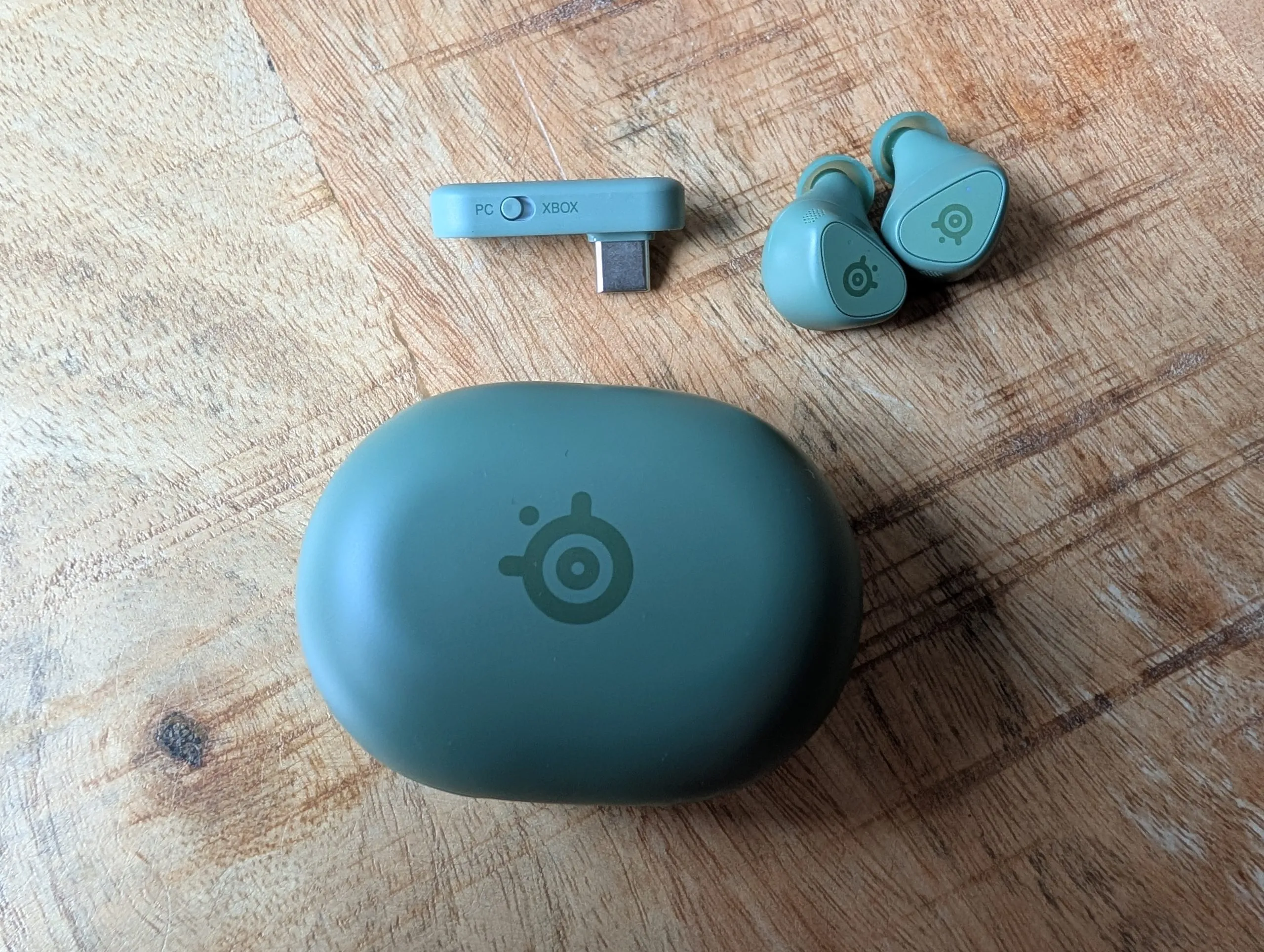 Auriculares, estuche y adaptador para PC y Xbox dispuestos sobre una mesa